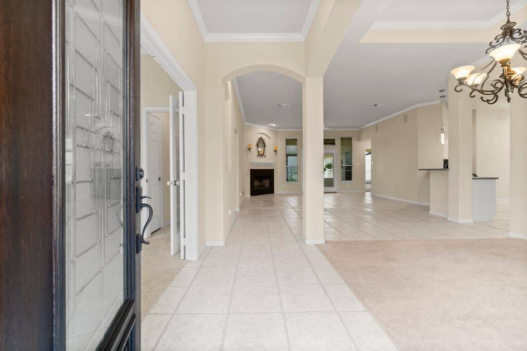 A welcoming brick front porch with large arched windows, a tiled floor, and a small garden area. The porch offers a cozy entrance, complemented by a wrought iron fence and a potted plant, providing a charming and inviting curb appeal.