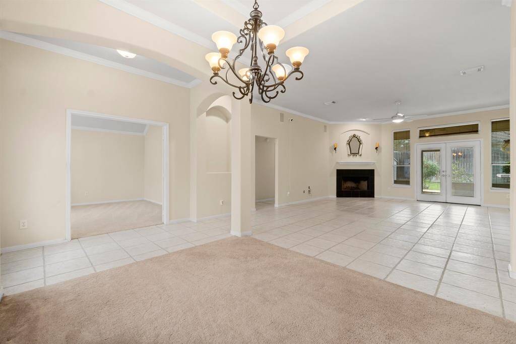 Formal dining features a soft carpeted floor, a large arched window with blinds, and a decorative chandelier, offering a cozy and well-lit space perfect for those family get togethers.