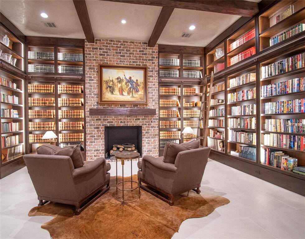 Beautiful floor to ceiling shelving, library ladder and lighting, brick fireplace