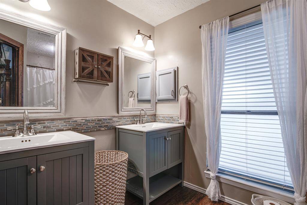 Master bath offers dual sinks with gray cabinets, stylish mirrors, and modern fixtures.