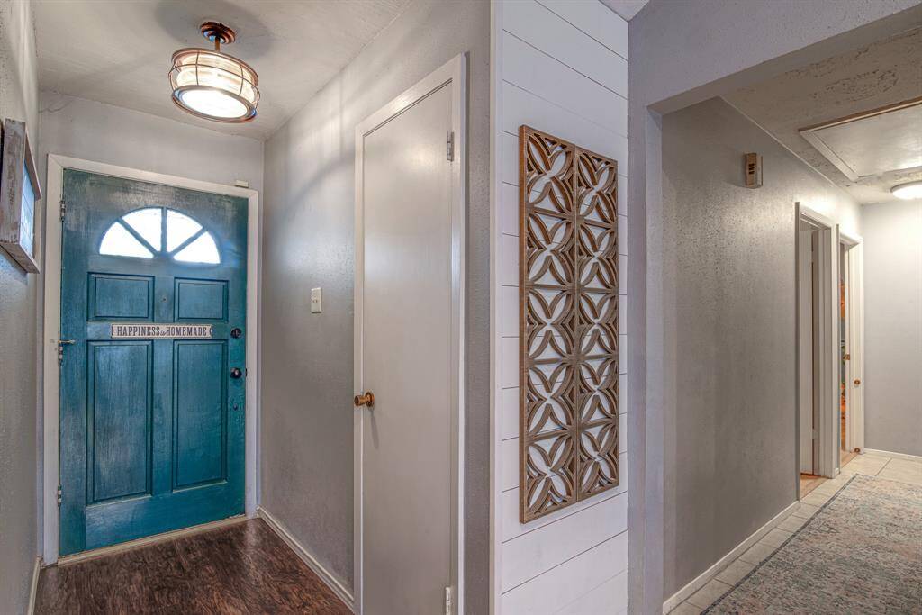 Welcoming entryway with a charming teal blue front door adorned. A panel with intricate design adds a touch of elegance to the space.