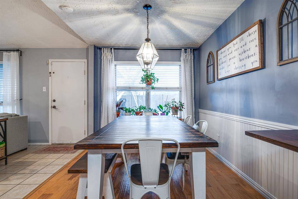 A large window allows natural light to brighten the space, complemented by a modern hanging light fixture.