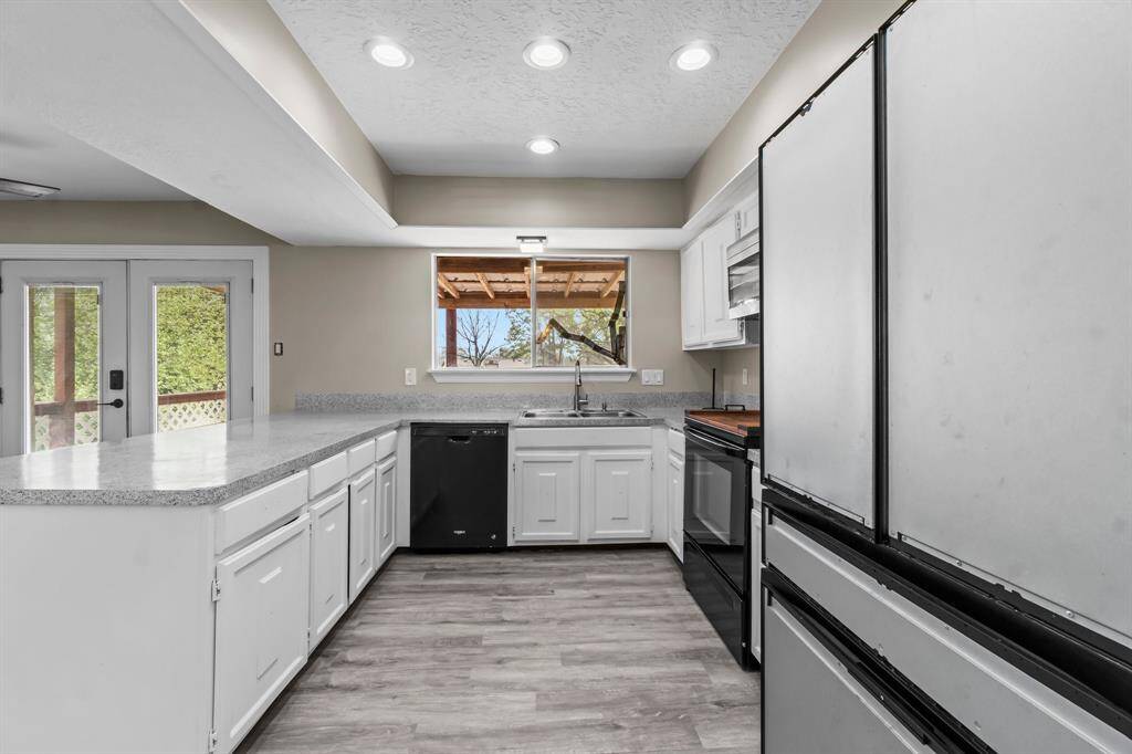Painted cabinets and windows overlooking the backyard. Note the recessed lighting.