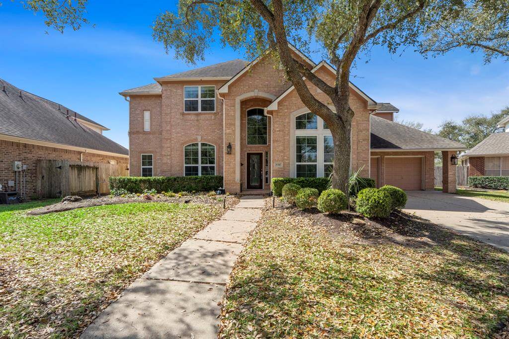 This is a charming two-story brick home with large windows and an inviting entrance.