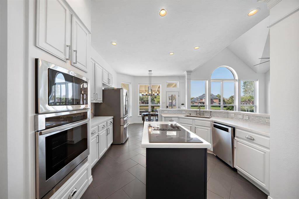 Bright, modern kitchen with stainless steel appliances, white cabinetry, and a central island.