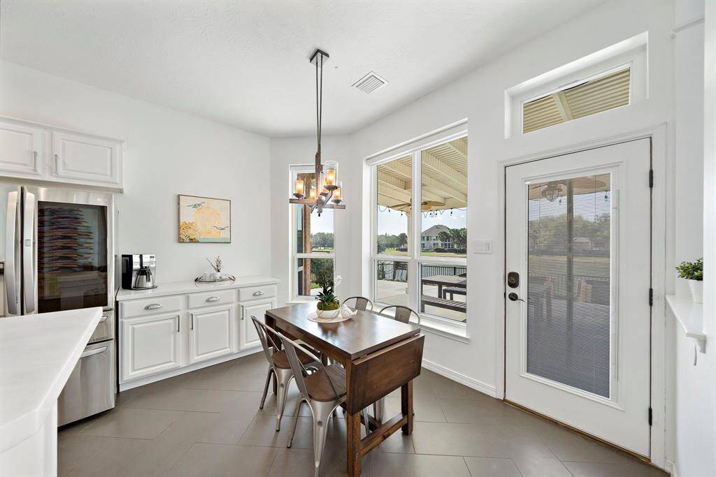 Bright kitchen nook with large windows, modern lighting, and a view of a spacious deck and serene water.