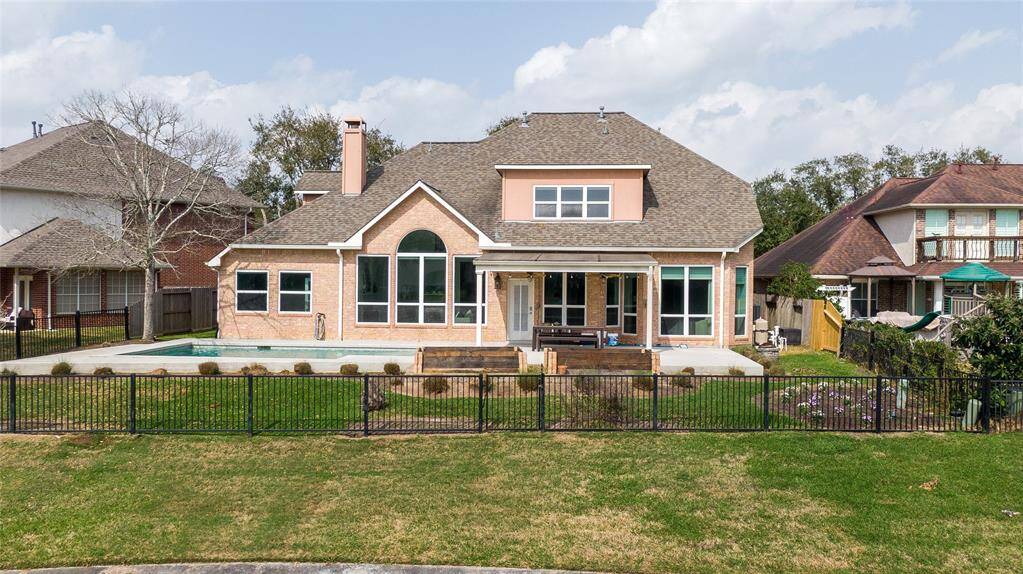 This beautiful two-story home features a spacious backyard with a fenced pool area, large windows for ample natural light, and a covered patio perfect for outdoor relaxation. The exterior boasts a charming, well-maintained look with a mix of brick and siding.