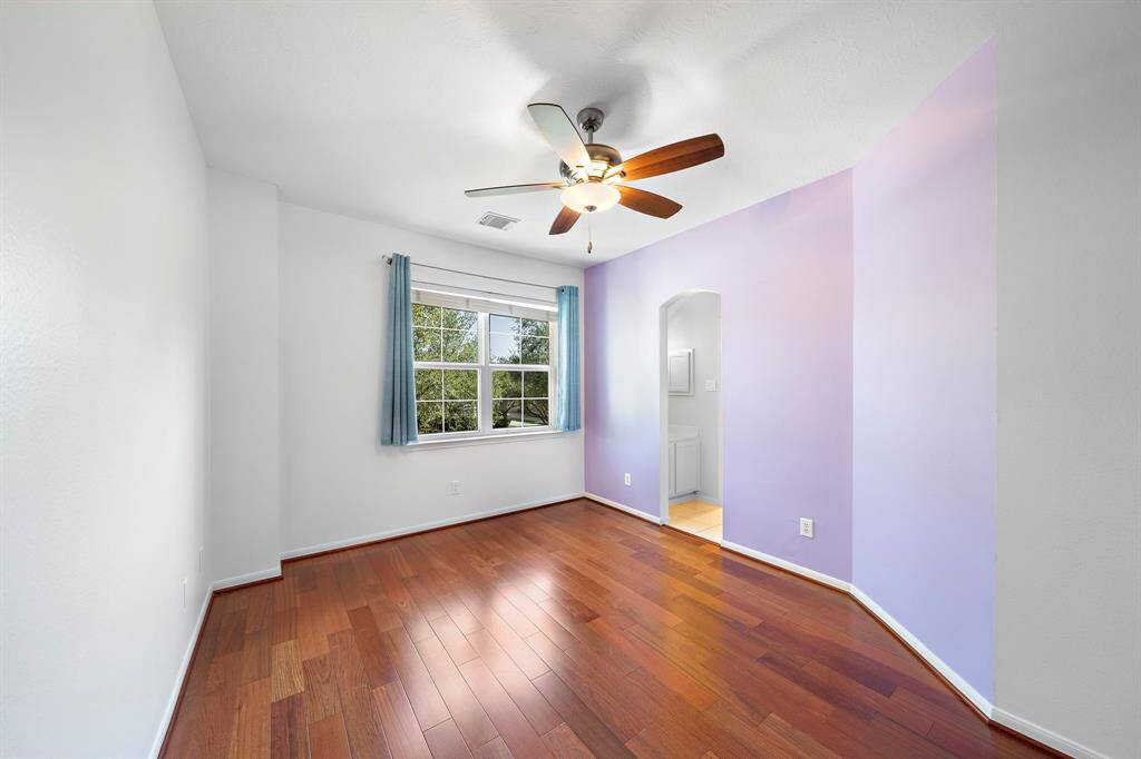 A soft lavender accent wall adds a touch of color, and an arched doorway leads to an adjoining space.