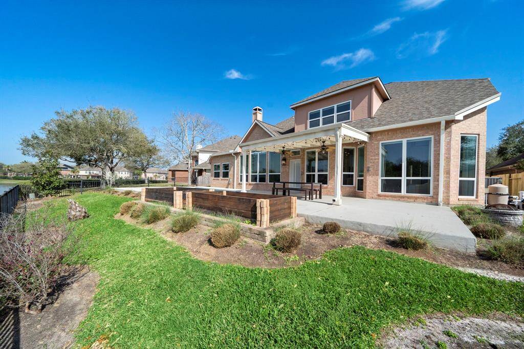 The exterior is brick with large windows offering plenty of natural light, and the yard is landscaped with greenery and a view of the water, providing a serene setting.