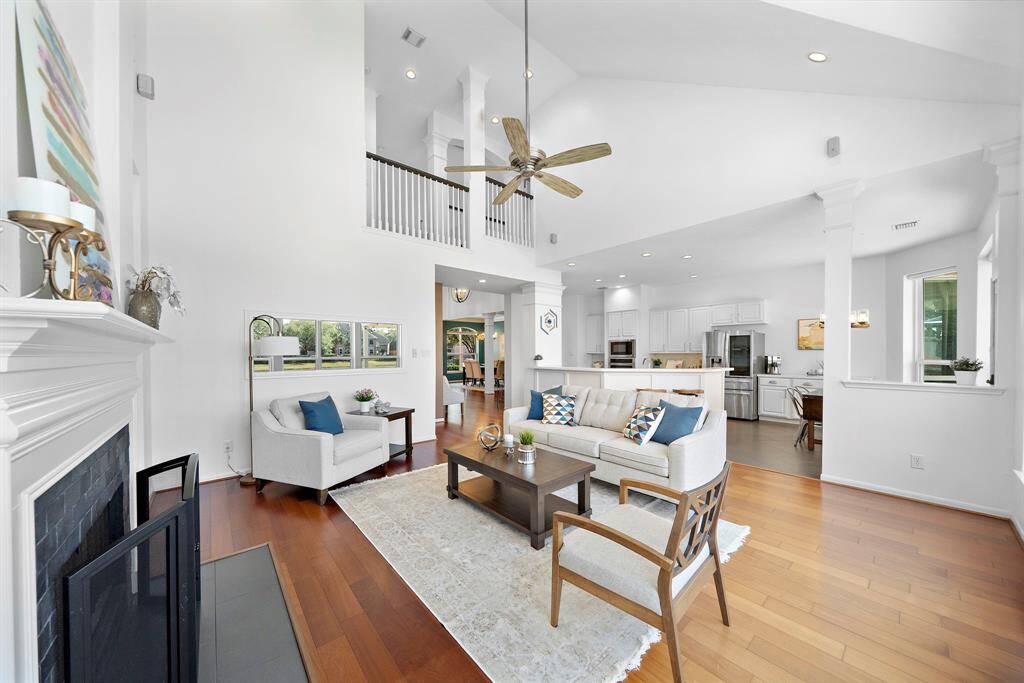 This spacious and bright living area features high ceilings, a cozy fireplace, and an open layout leading to a modern kitchen. Natural light floods the room, highlighting a stylish interior design, perfect for entertaining.