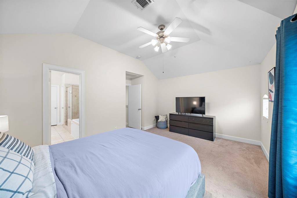 Vaulted ceilings and plush carpeting amplify this bedroom's spacious feel. An ensuite bath and walk-in closet offer privacy, while neutral tones create a serene atmosphere.