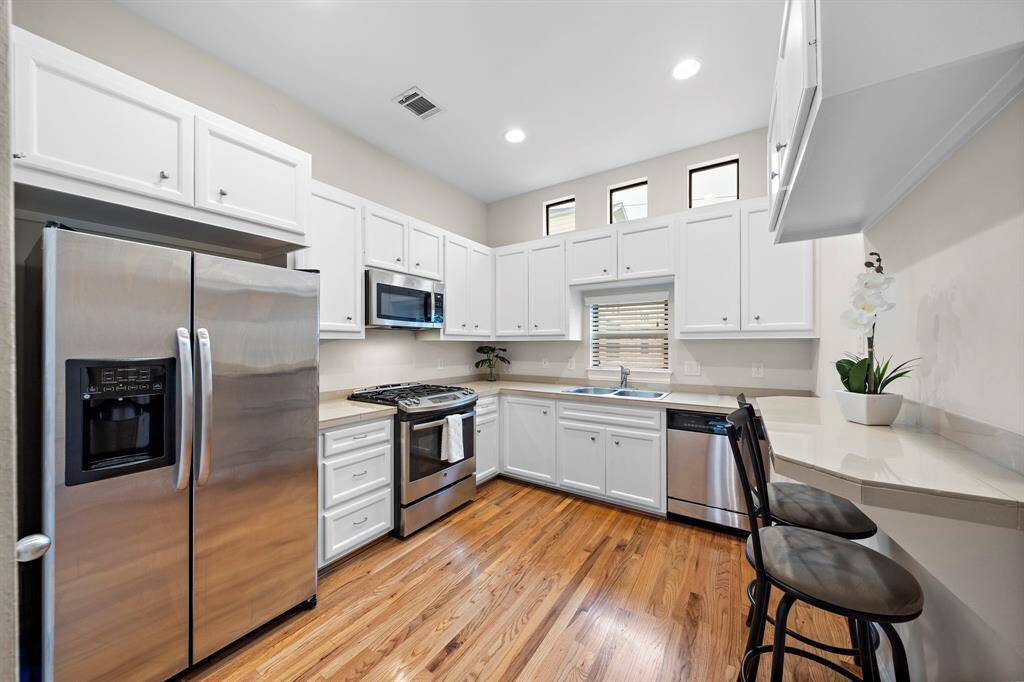 Stainless-steel appliances and ample storage define this kitchen. Easy access to a breakfast bar provides casual dining space, while the undermount sink provides a seamless countertop.