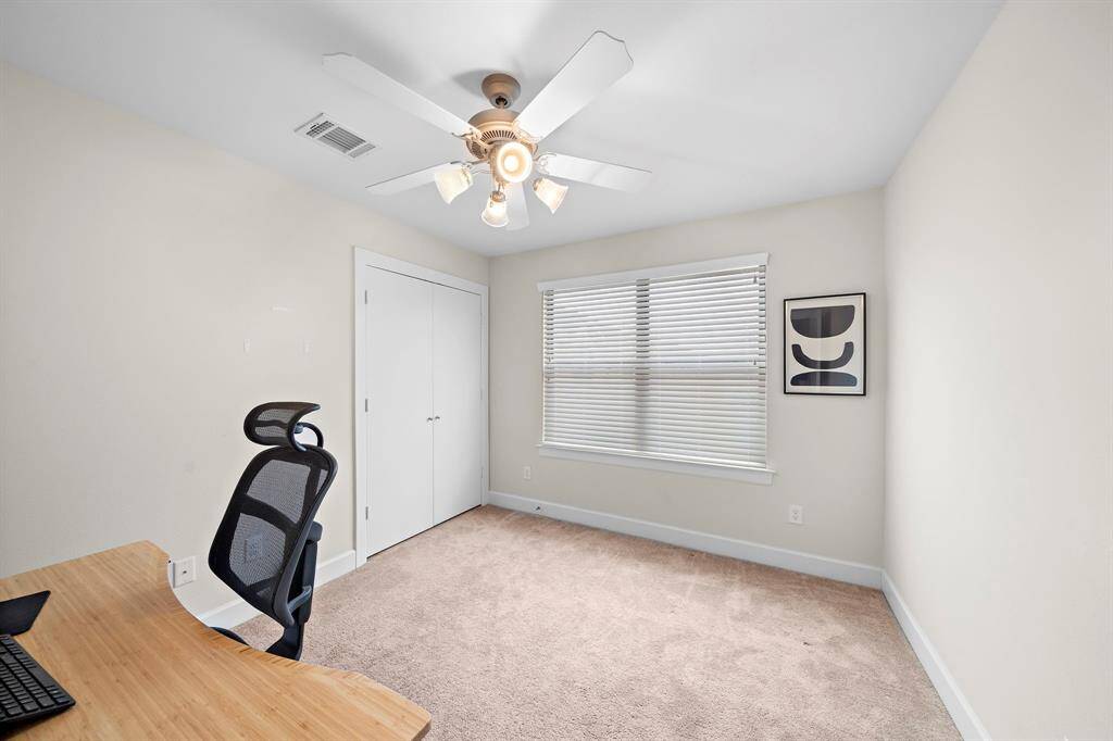 Convert a spare bedroom into a useful home office. This flex space features neutral carpeting, a lighted ceiling fan, and closet for storage.