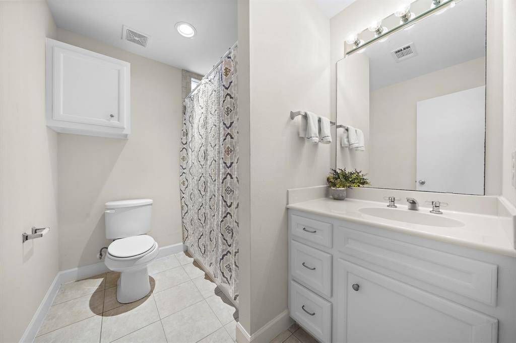 This bathroom is equipped with a shower, toilet, and vanity featuring storage beneath. A neutral color palette makes for a clean and calming space.