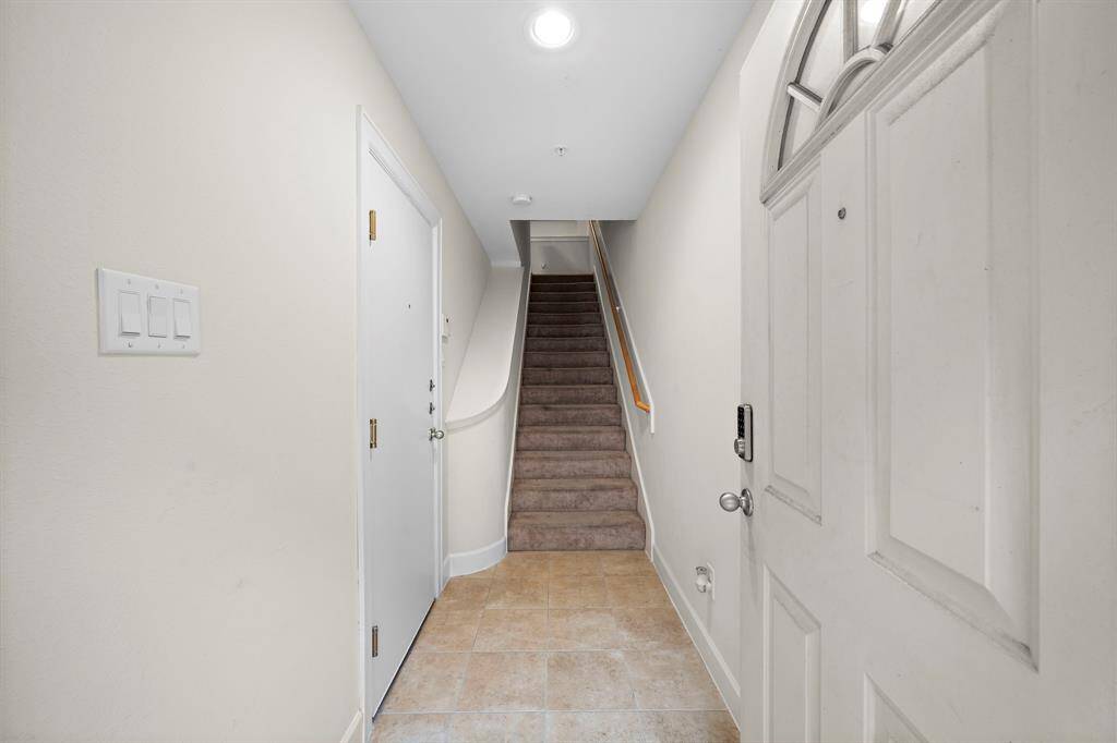 The home's entrance features neutral tile flooring that extends into the hall. Conveniently located stairs with carpet runner lead to the upper floors of this townhome.