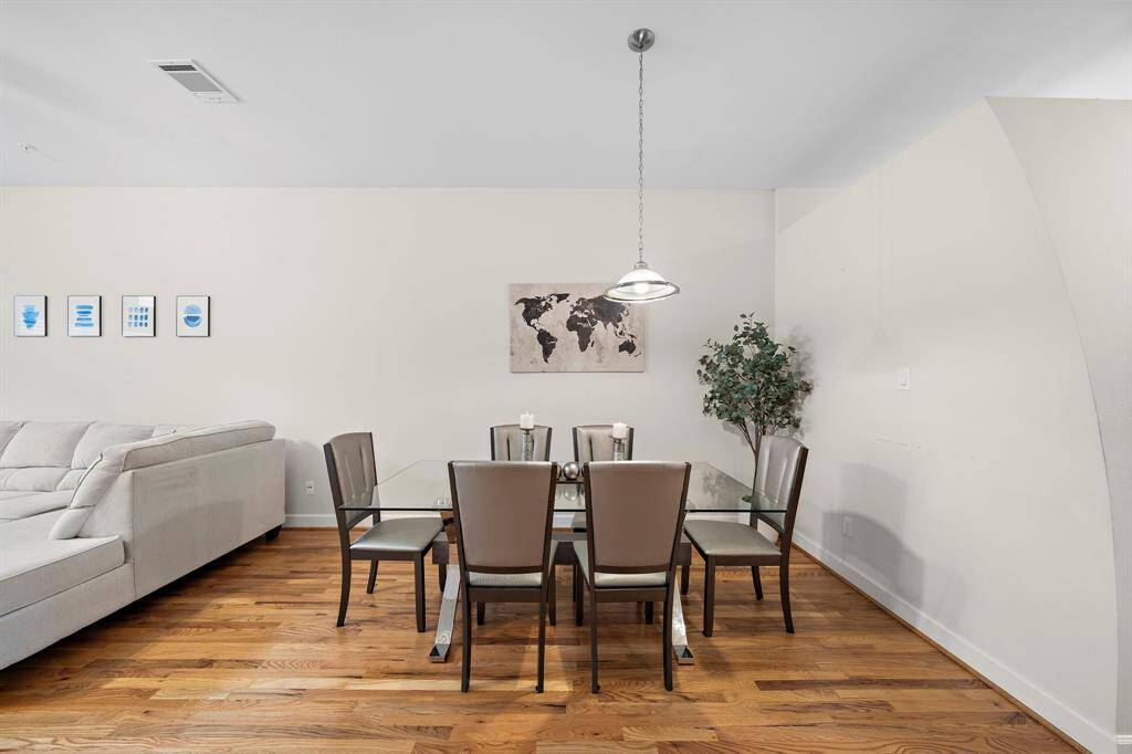 The dining area with seating for six sets an elegant tone. An overhead pendant light complements the area, while wood flooring adds warmth and sophistication.