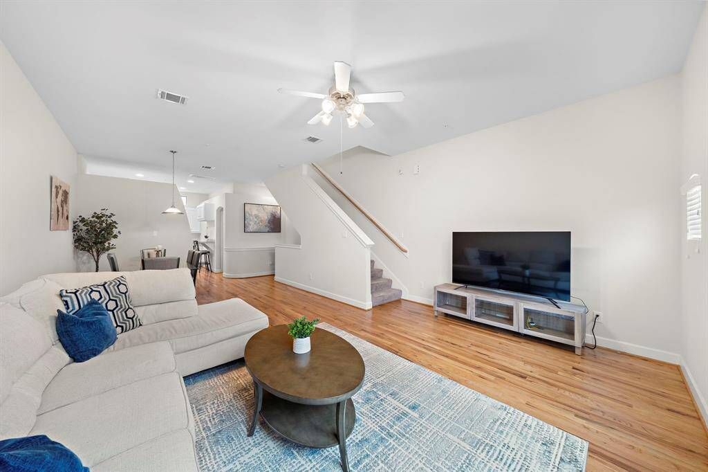 Entering from the foyer, the living area spotlights hardwood flooring with an effortless flow. The space offers an open layout with plentiful lighting and a staircase that accesses the upper floors.
