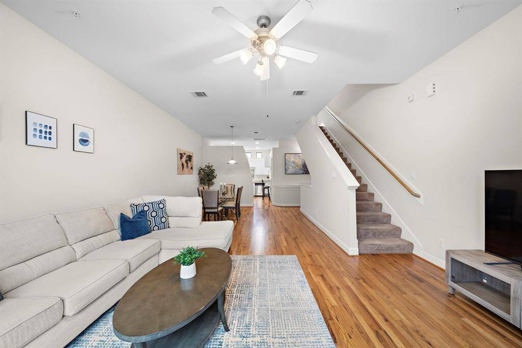 An open floor plan showcases hardwood floors, seamlessly linking the living area to the dining space. Sunlight fills the space, highlighting the neutral tones ready for personalization.