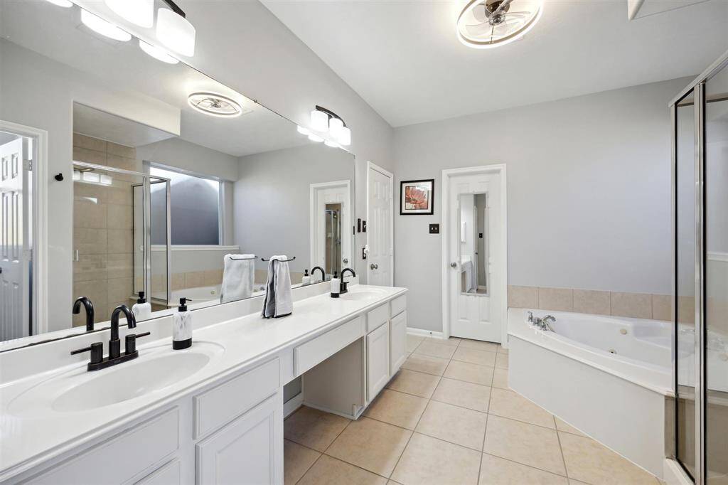 The primary bathroom features a vanity with 2 sinks.  jetted tub with separate shower, tile flooring, ceiling fan!, linen closet and two walk-in closets!