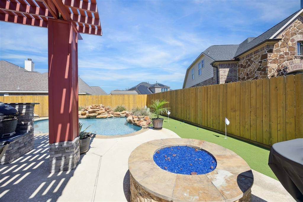 Just beyond the pergola is this Stone Fire-pit tied into the natural gas!  And here you can see one side of the putting green.  The pool is a heated chlorine pool with stone waterfalls and multicolor lighting, with custom Pebble Tec coating.