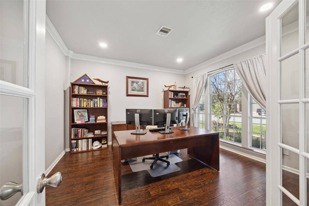 Through the French Doors and into the study/office. Beautiful wood laminate flooring, and a wall of windows looking out to the front yard. Fresh paint through the entire house was done in 2023. Recessed lighting and crown molding add a beautiful touch.