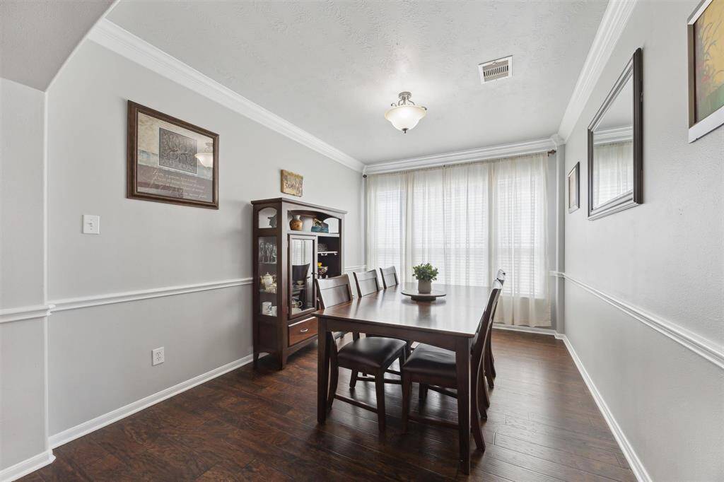 Upon entering the house, the office/study is on the right, and just past that is this formal dining room. Gorgeous wood laminate flooring, crown molding, chair rail, and wall of windows.