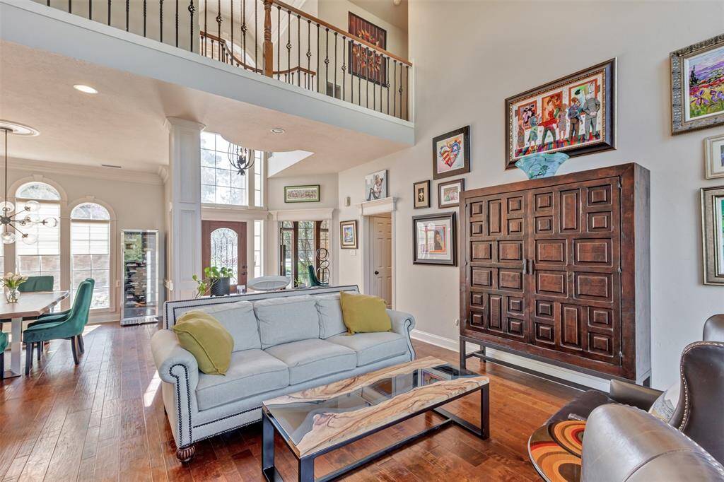This view of the living room showcases the elegant wood flooring and a stylish mix of modern and classic features creating a warm and inviting atmosphere. The balcony with wood and iron adds architectural interest.
