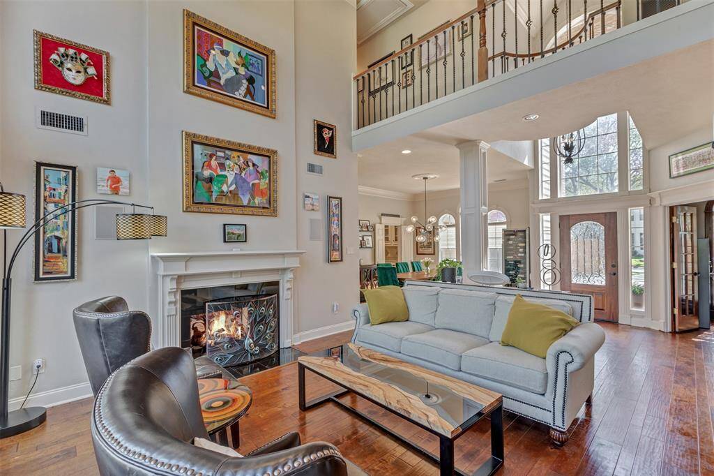 This inviting living space features high ceilings and abundant natural light. The open floor plan showcases a cozy sitting area and beyond is the dining area ideal for entertaining. Large windows and a two-story foyer enhance the bright and airy ambiance.