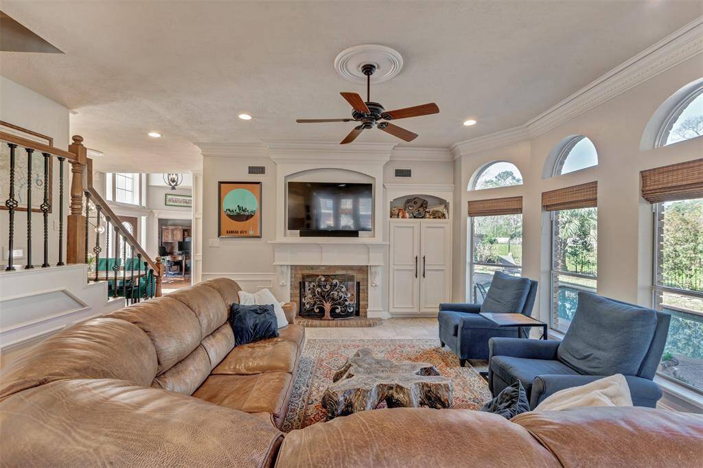 The spacious family room features a cozy fireplace and built-in entertainment center, complemented by large arched windows offering plenty of natural light and views of the outdoors and creates a welcoming atmosphere ideal for relaxation and gatherings.