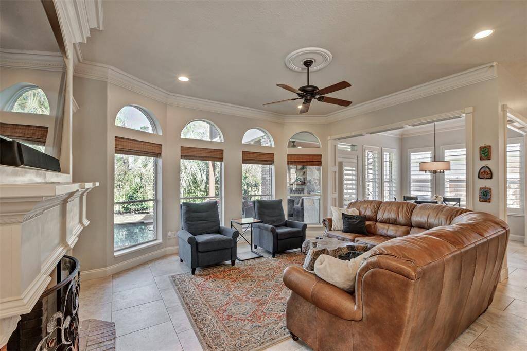 This kitchen features elegant white cabinetry, granite countertops, and a spacious island with a cooktop. Stainless steel appliances, including a double oven and refrigerator, provide modern convenience, while large windows offer ample natural light. Perfect for cooking and entertaining.