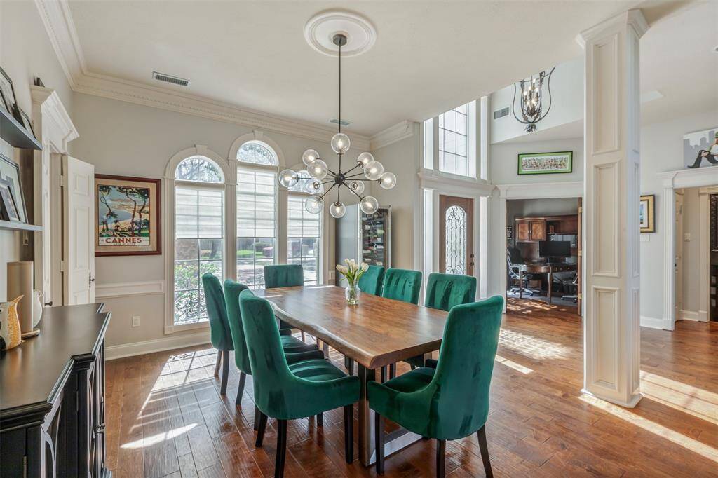 The dining area is accented by a modern chandelier and is illuminated by large arched windows, offering plenty of natural light. The open flow between foyer, dining and living room creates a welcoming atmosphere.