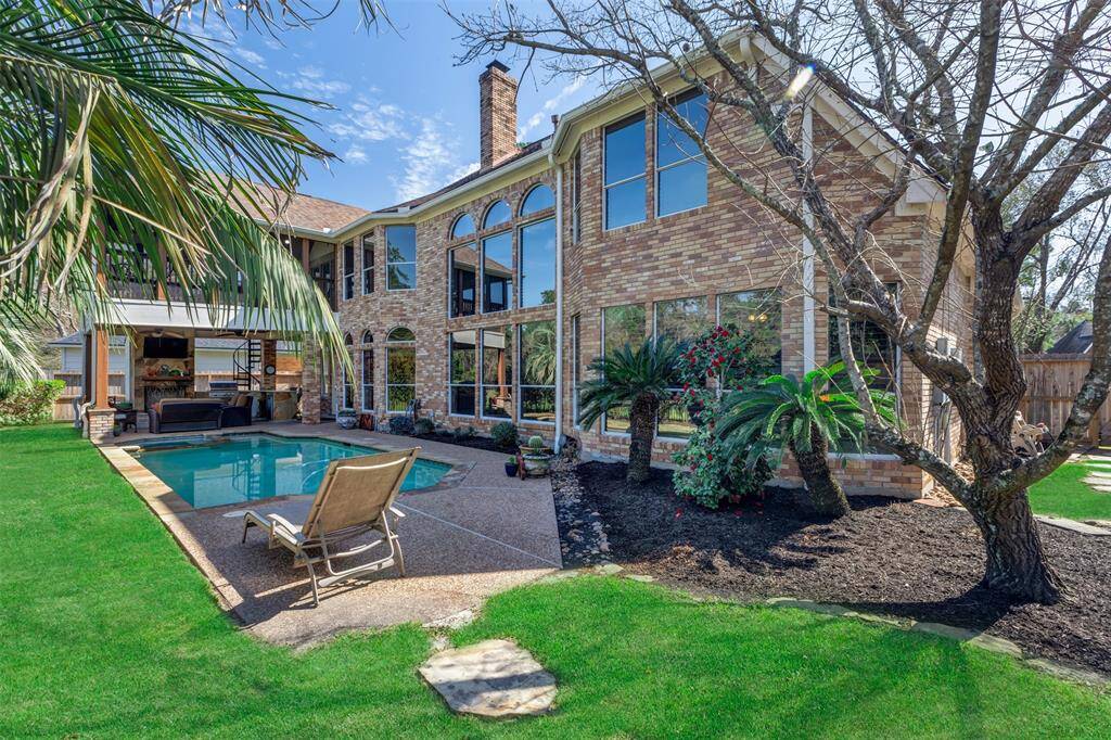 This gorgeous two-story brick home has large windows, offering a view of a well-maintained backyard. The outdoor space features a sparkling pool and spa, lush greenery, and a covered outdoor living area area, ideal for relaxation and entertaining. This could be your next home!