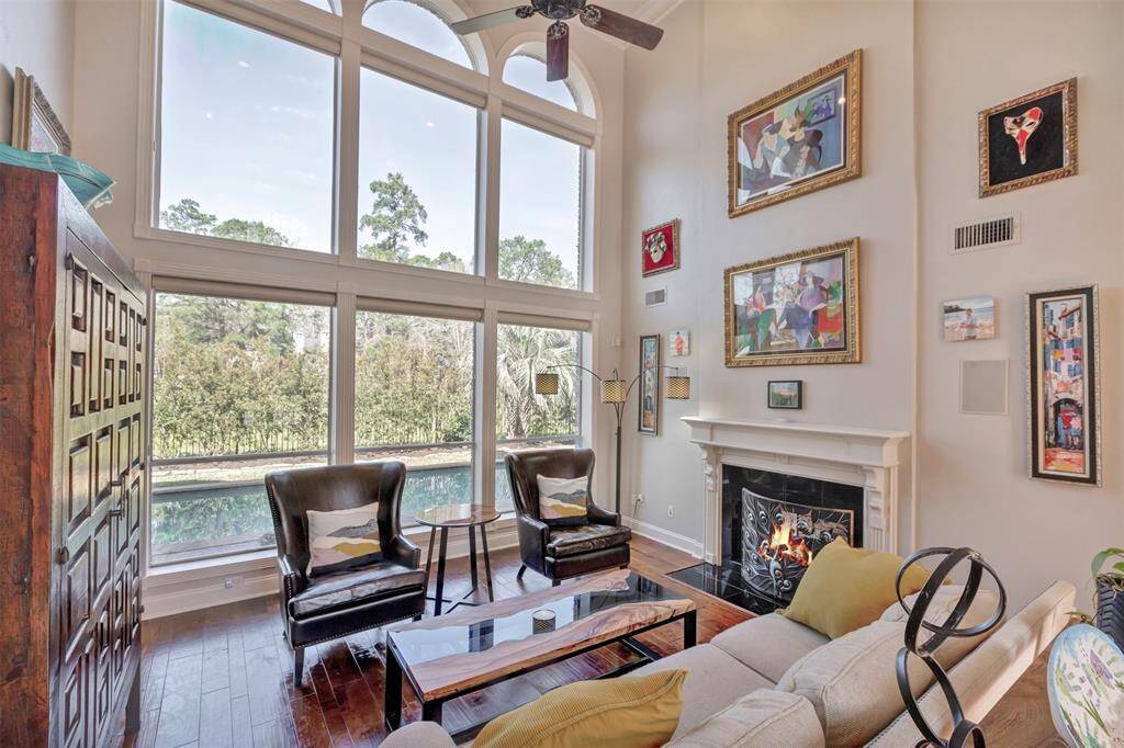 The living room has a cozy, dual sided fireplace, high ceilings and large arched windows offering a scenic view of the private pool area surrounded by lush landscaping backing to the greenbelt reserve.