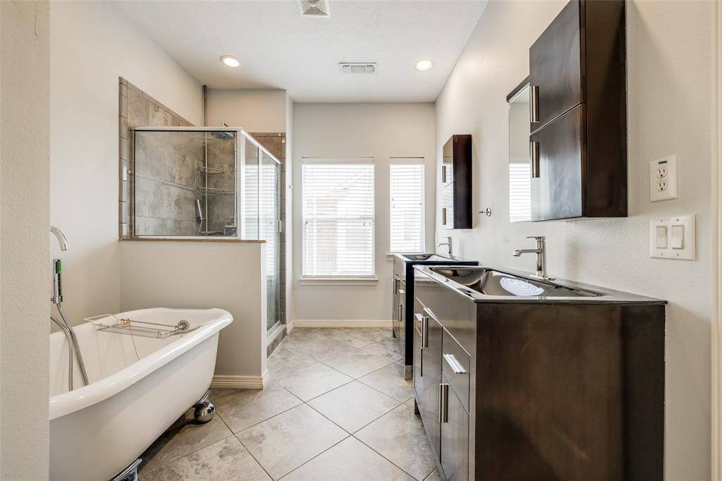 Primary bath has double vanity, tile floors, soaking tub, and walk-in shower.