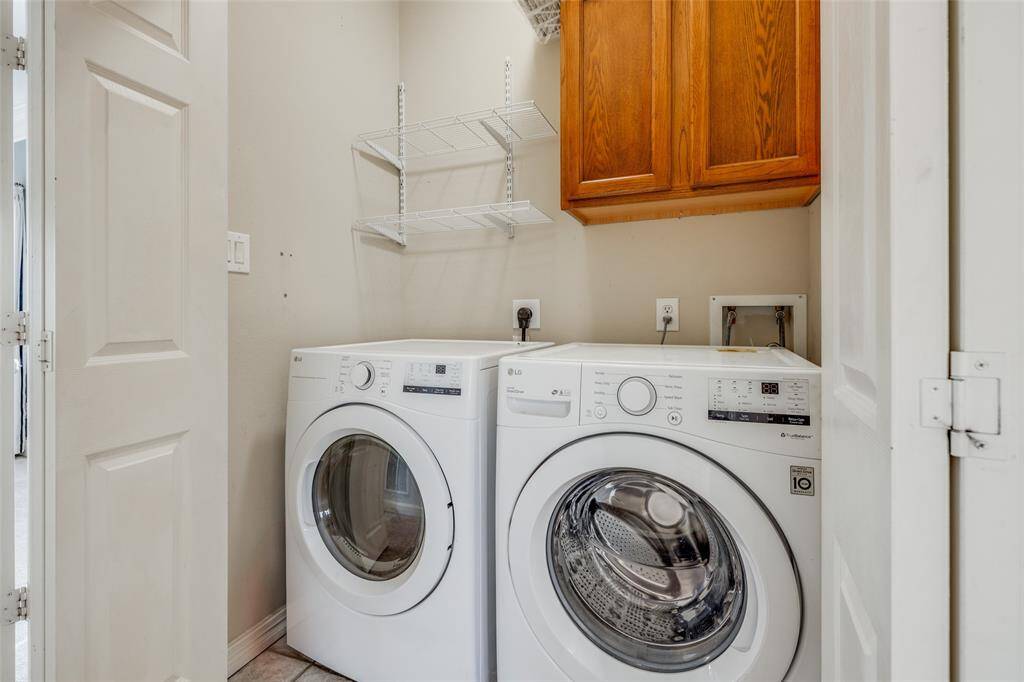 Laundry closet has full size washer and dryer that stays with the home and cabinets and shelving above.
