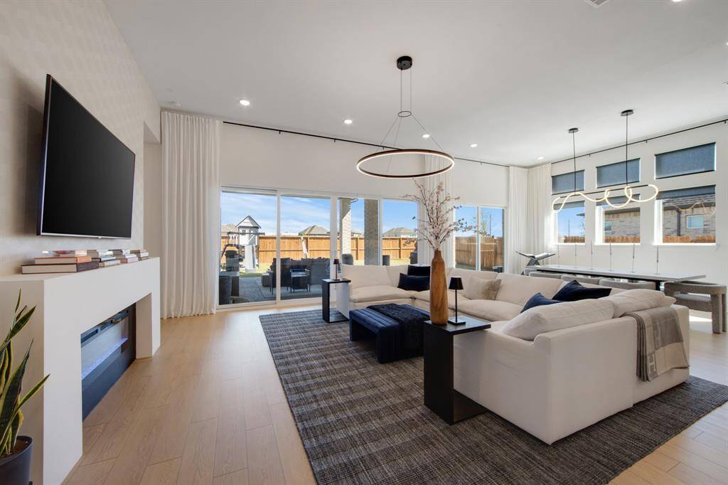 The oversized slider doors seamlessly connect the living room to the backyard, offering easy access to outdoor living and filling the space with natural light. The room is beautifully complemented by custom drapery, adding a touch of luxury and privacy while enhancing the overall design.