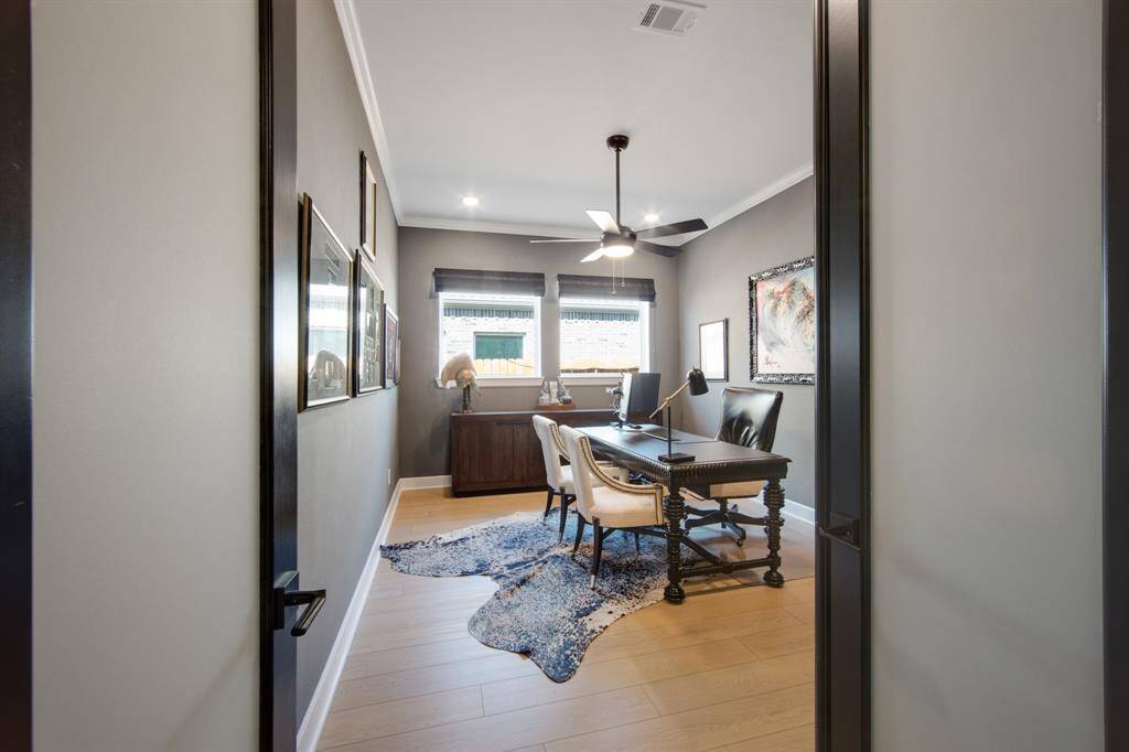 The private office is a sophisticated retreat, featuring frosted dual doors for added privacy, along with crown molding that adds a touch of elegance. A ceiling fan ensures comfort, making it an ideal space for productivity or quiet work.