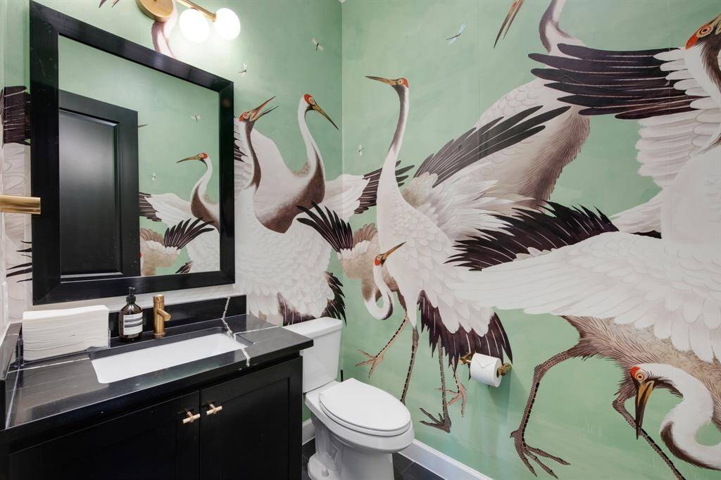 The powder bathroom is a stylish retreat, featuring stunning wallpaper that adds a bold, sophisticated touch to the space. A framed mirror and quartz countertops elevate the design, creating a chic and luxurious atmosphere.