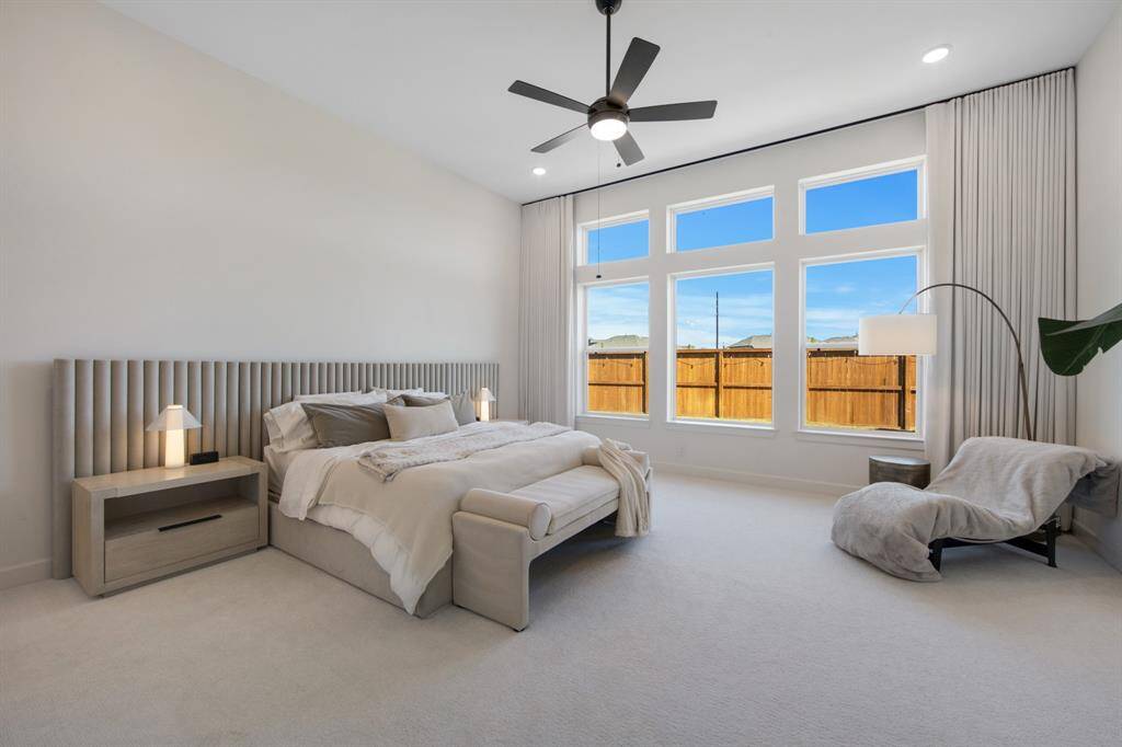 The primary retreat features plush carpeting that adds warmth and comfort, complemented by custom drapery that enhances the room’s elegance. With its soaring tall ceiling, the space feels open and airy, creating a serene and luxurious atmosphere.