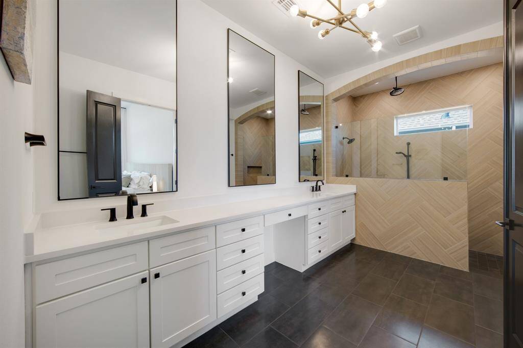 The primary ensuite is a spa-like retreat, featuring stunning tile flooring that adds a touch of sophistication. Dual sinks are paired with framed mirrors, offering both practicality and style, while the sleek LED light fixture provides a modern and energy-efficient glow. Upgraded fixtures throughout elevate the space, creating a luxurious and serene atmosphere.