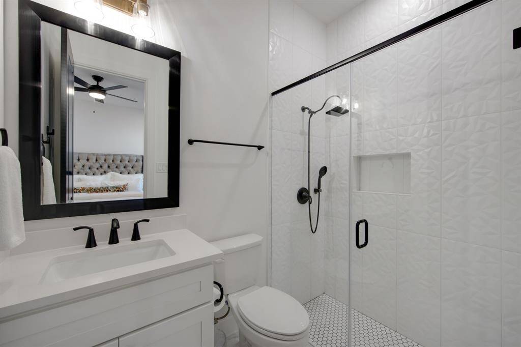 The guest ensuite features a sleek framed mirror and a shower tiled from floor to ceiling, creating a polished and modern look. A thoughtfully designed niche adds both style and practicality, offering a convenient space for toiletries.