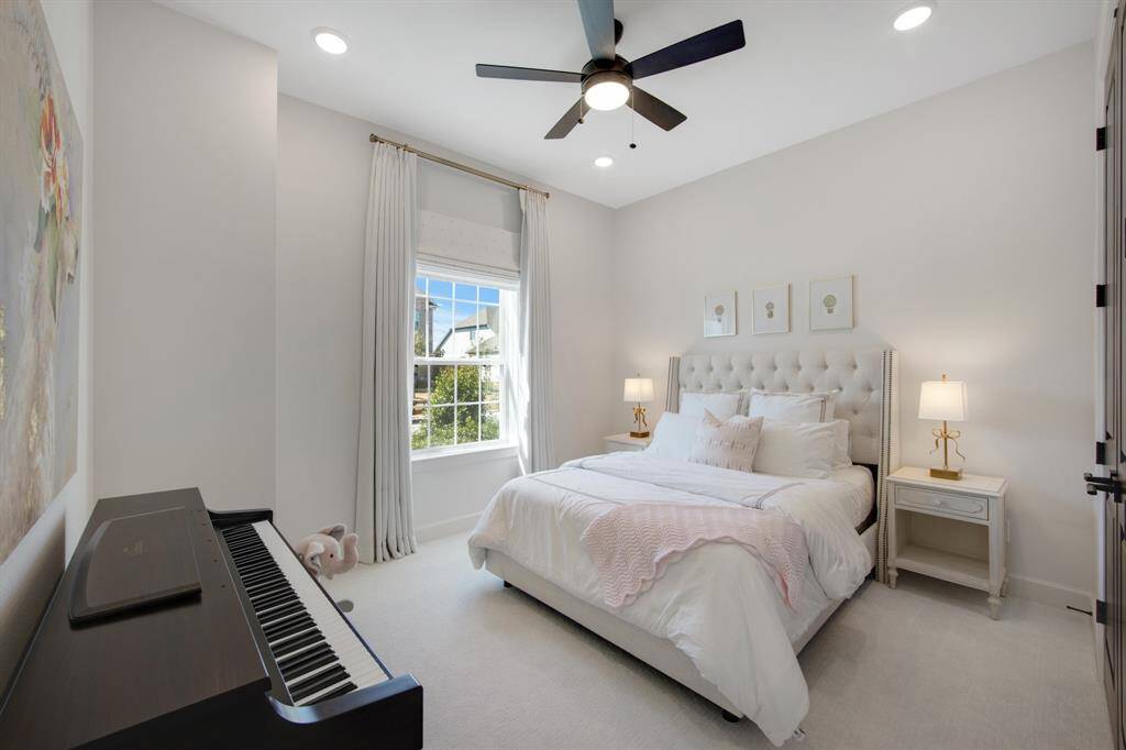 The secondary bedroom is comfortably appointed with plush carpeting and a ceiling fan, creating a cozy and cool atmosphere for rest, and features cellular shades for enhanced light control and privacy.