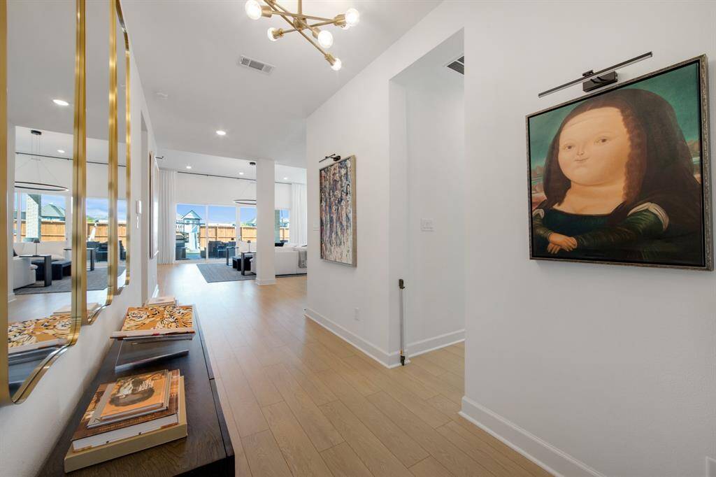 The grand entryway features a long, open design with soaring tall ceilings, creating an impressive first impression. A beautiful light fixture hangs above, adding elegance and warmth to the space as it welcomes you into the home.