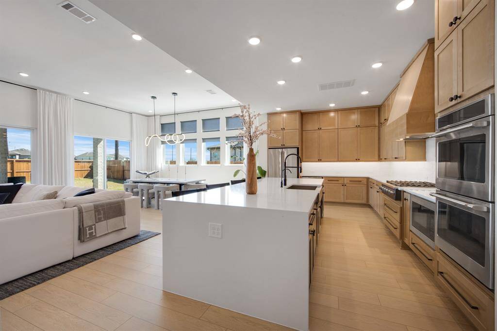 The large island features a stylish farmhouse sink and a stunning quartz waterfall edge, adding both functionality and a touch of luxury to the kitchen.