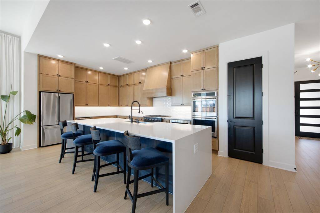 The kitchen is adorned with beautiful cabinets that extend all the way to the ceiling, offering ample storage and a sleek, modern look. Under-cabinet lighting highlights the craftsmanship, while the double ovens provide convenience for cooking large meals. Additionally, the walk-in pantry ensures there's plenty of space for all your essentials, making this kitchen both functional and elegant.