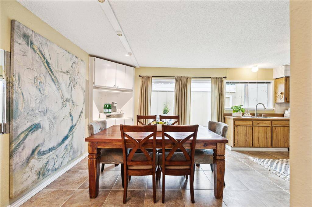 This is a spacious dining room with tile flooring, featuring built-in cabinetry, shelves and ample natural light from a large sliding glass door.
