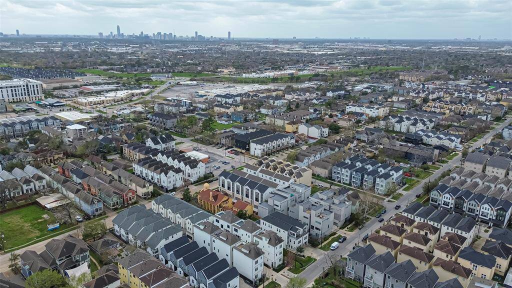 This aerial view highlights a vibrant suburban neighborhood with a mix of modern townhouses and single-family homes, offering a strong sense of community. The neatly arranged streets and proximity to the city skyline ensure convenient access to urban amenities.