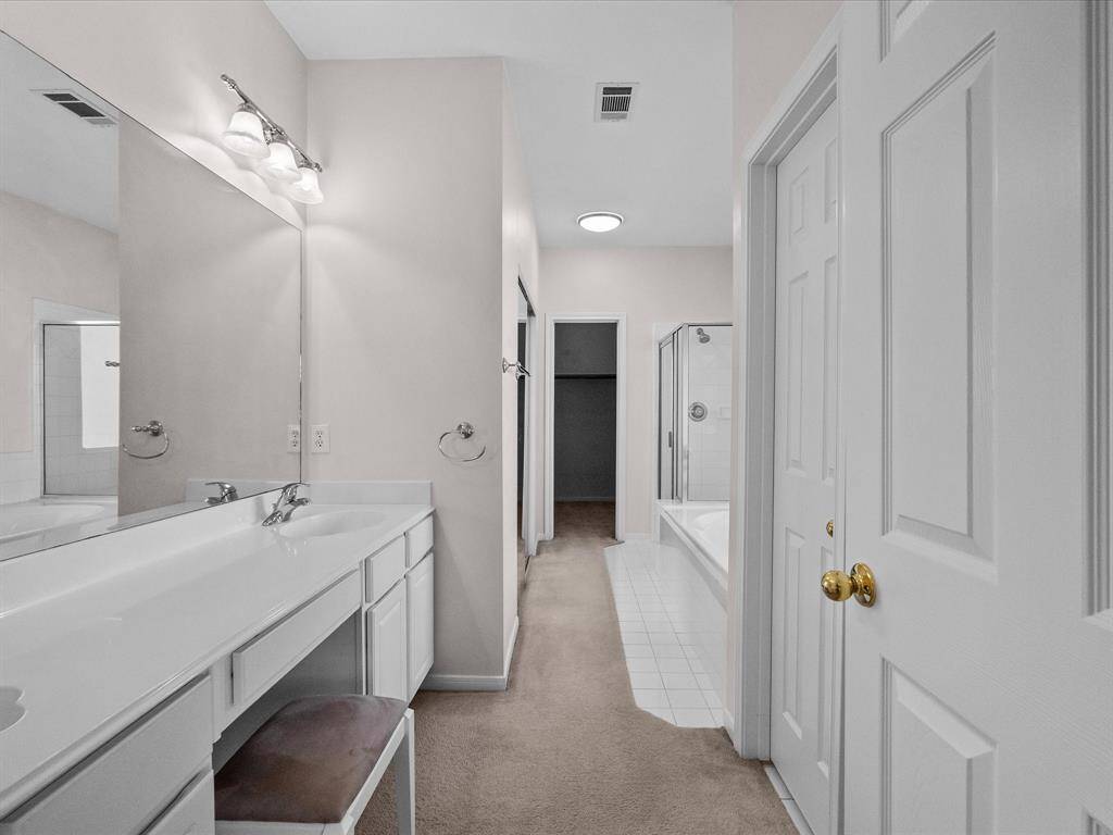 Spacious en-suite bath featuring a vanity area, soaking tub, separate shower, and dual closets one being full walk in.