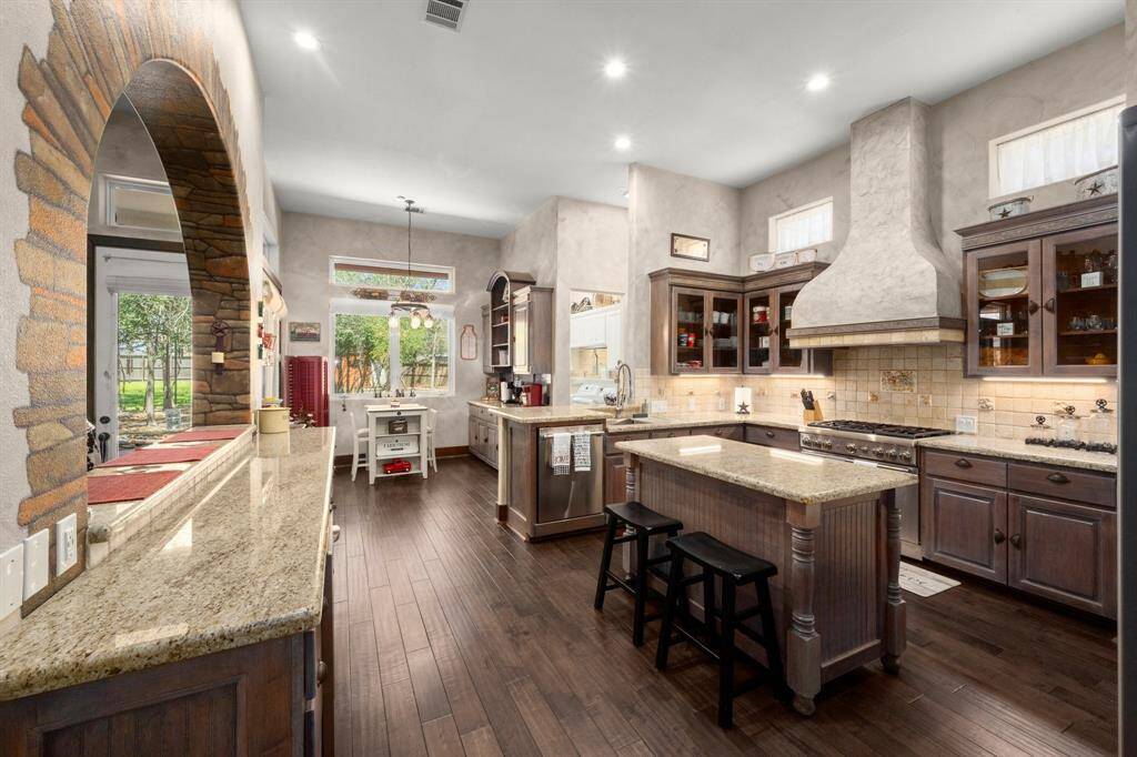 Kitchen with granite countertops and glass door cabinets.