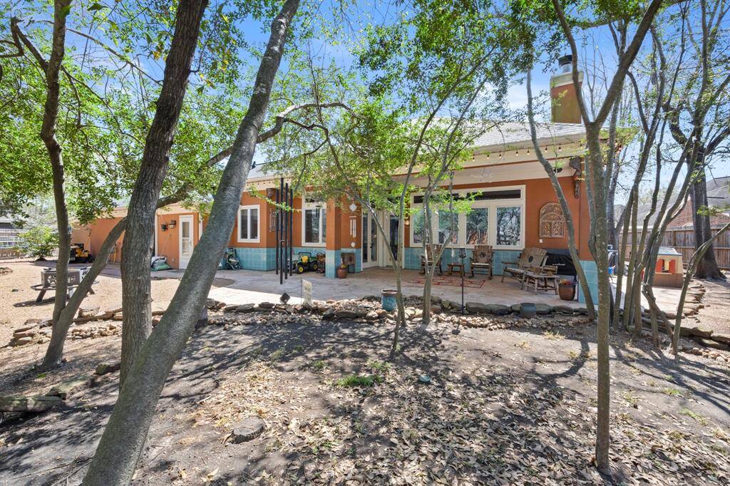 Large covered back patio facing beautiful back yard with trees.